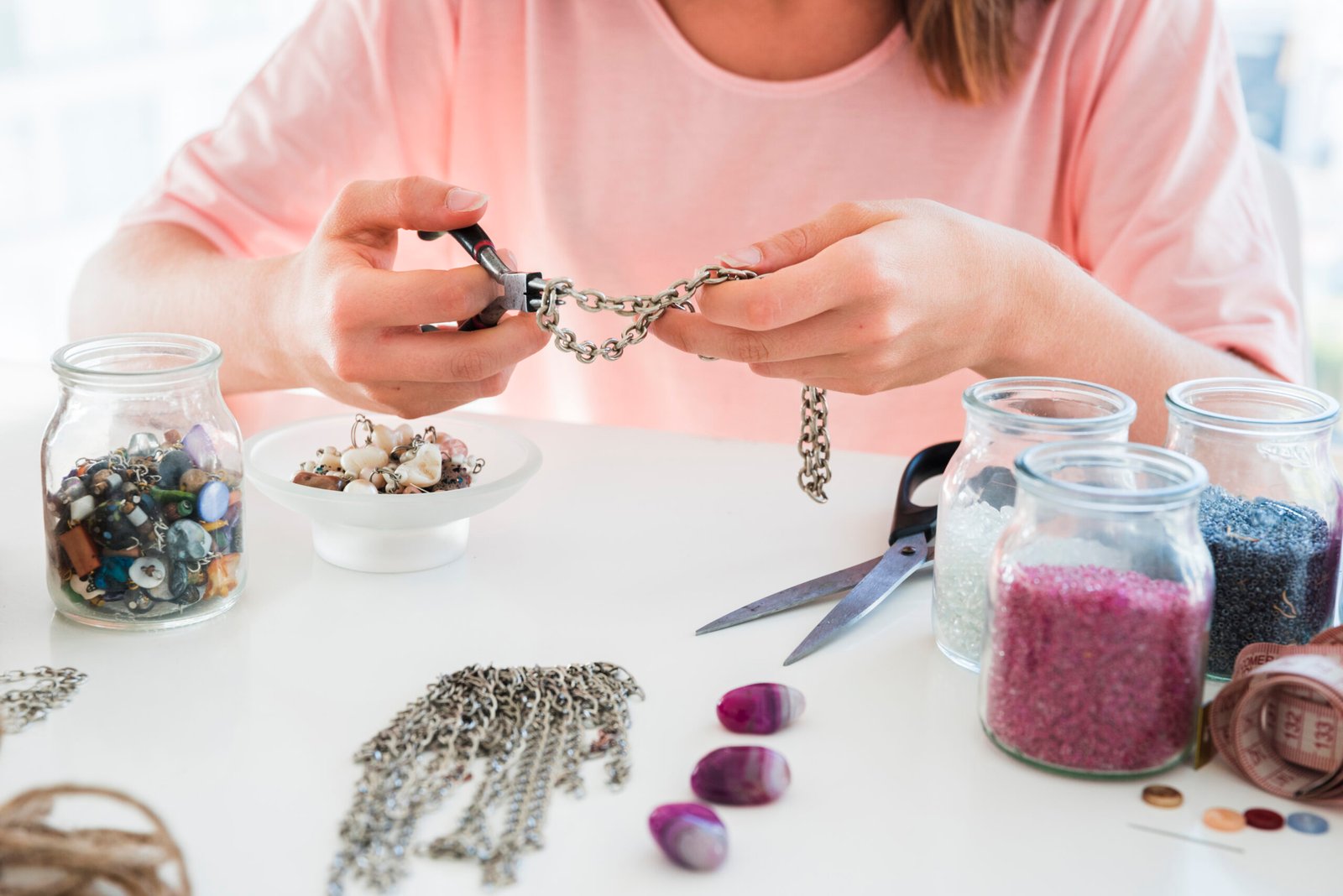 Close up woman making handmade bracelet with chain beads scaled